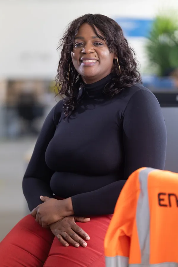 Portrait d'une chargée de projet souriante avec une veste de sécurité Enedis en arrière-plan