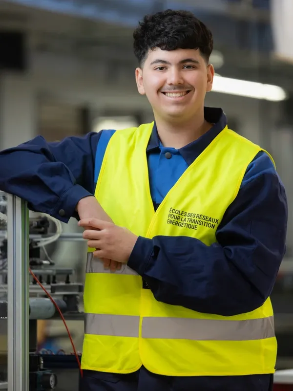 Aymane en gilet de sécurité souriant dans un atelier technique