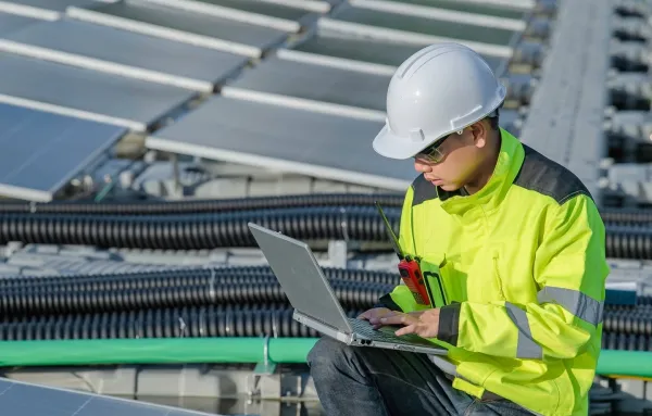 Ingénieur en génie électrique inspectant une installation de panneaux solaires avec un ordinateur portable