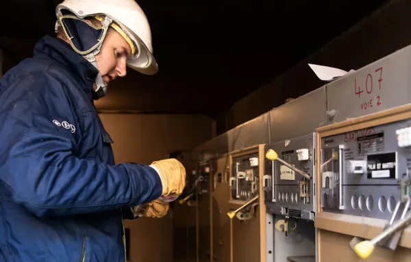 Technicien d’exploitation des réseaux inspectant un tableau électrique avec casque et gants de sécurité