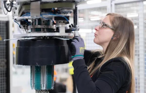 Opératrice régleuse usineuse en train de contrôler une machine industrielle