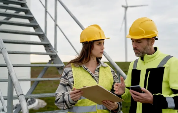 Techniciens en discussion sur un site éolien, avec casque et gilet de sécurité