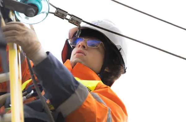 Monteur de réseaux électriques travaillant sur des câbles électriques avec harnais et casque