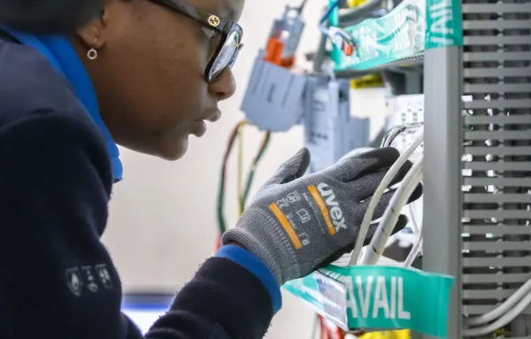 Technicienne en maintenance électrique industrielle travaillant sur un panneau de câblage